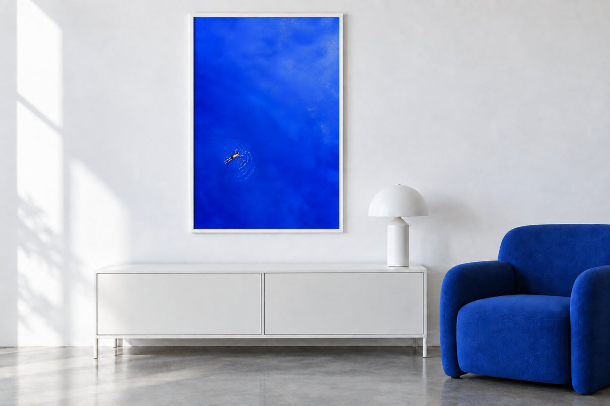 Dasselbe weiß-blaue Wohnzimmer ohne Bücherstapel und mit demselben Schwimmerposter