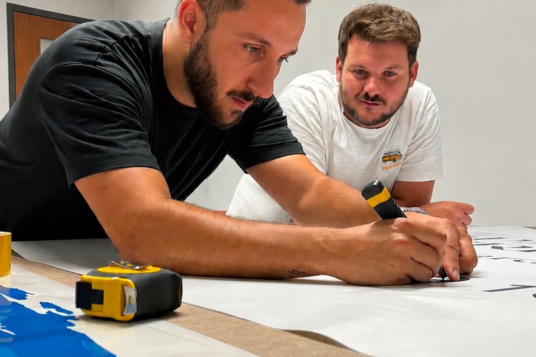 Une affiche coupée à la règle sur l'établi de l'atelier, regardée à contre-jour